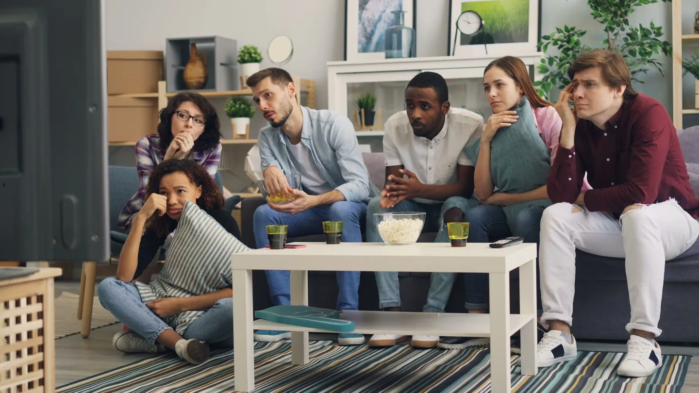 Gruppo di amici italiani che guarda un film sul divano con popcorn