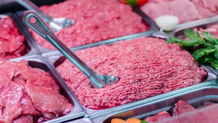 carne macinata fresca in vaschetta da supermercato accanto a carne tritata in macelleria su tagliere