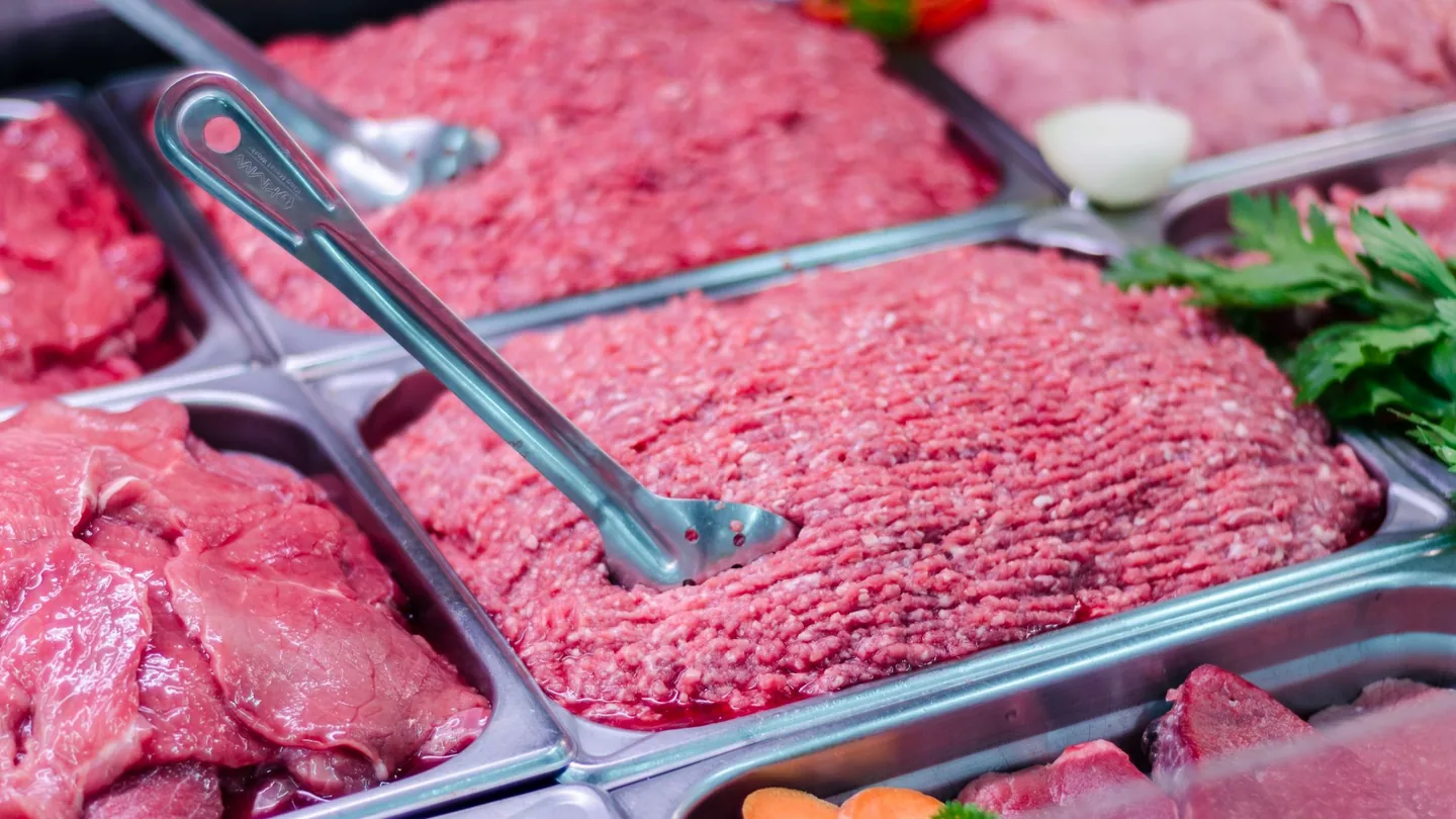carne macinata fresca in vaschetta da supermercato accanto a carne tritata in macelleria su tagliere
