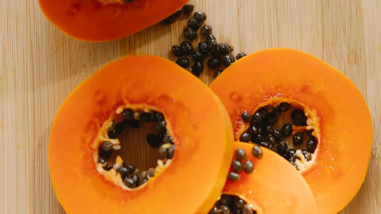 Papaya fresca tagliata a metà con semi neri su un tagliere in cucina