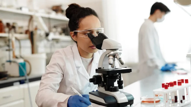 ricercatrice in laboratorio che analizza campioni di DNA umano al microscopio su sfondo di grafici genetici